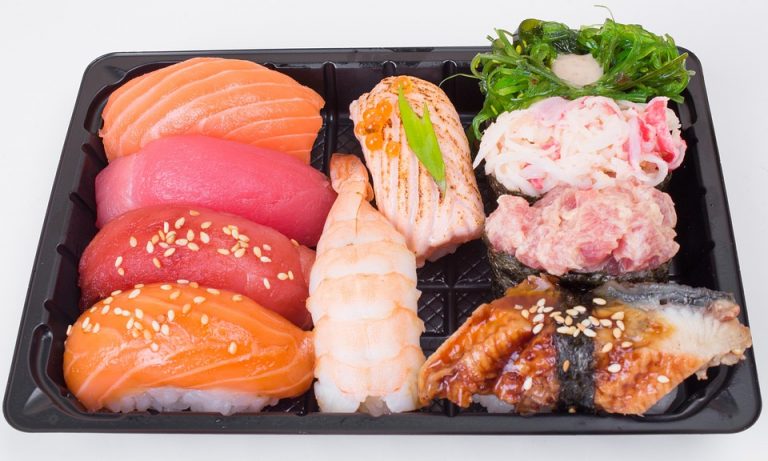 Assorted sushi platter with salmon, tuna, shrimp, and seaweed salad.