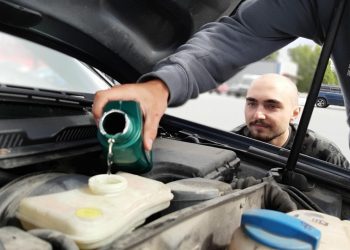 Filling car coolant in the engine compartment.