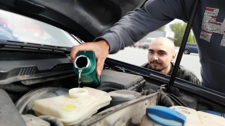 Filling car coolant in the engine compartment.