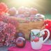 Basket of apples with flowers and cinnamon apple mug on a sunny table.