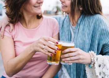 Two friends cheer with glasses of beer, smiling enjoying a moment to beer balance hormones