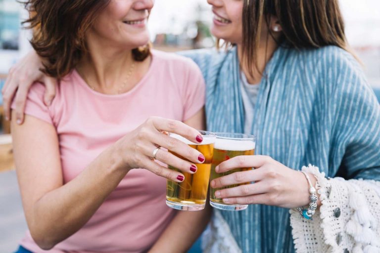 Two friends cheer with glasses of beer, smiling enjoying a moment to beer balance hormones
