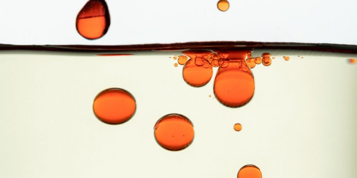 Red oil droplets floating in clear liquid.