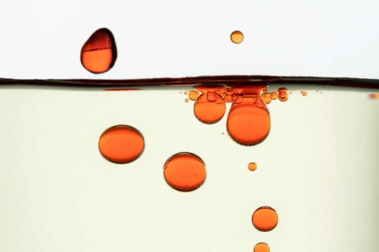 Red oil droplets floating in clear liquid.