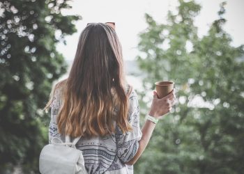 Woman with long hair enjoying outdoor coffee.