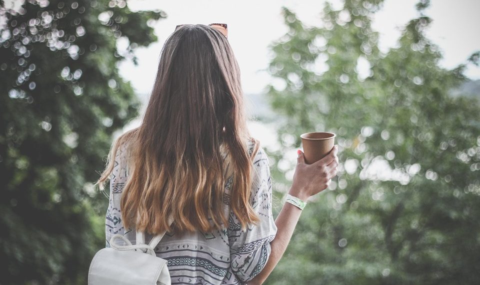 Woman with long hair enjoying outdoor coffee.