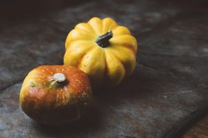 Two small pumpkins on a rustic table surface.