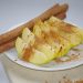 Apple slices with cinnamon and whole cinnamon sticks on a plate.