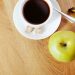 Coffee with sugar cubes, green apple, and banana on wooden table.