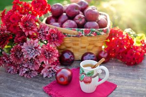Basket of red apples with flowers and apple cinnamon tea on table.