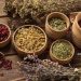 Dried herbs and berries in wooden bowls on rustic table.