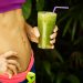 Woman holding green smoothie, focusing on fitness and health.