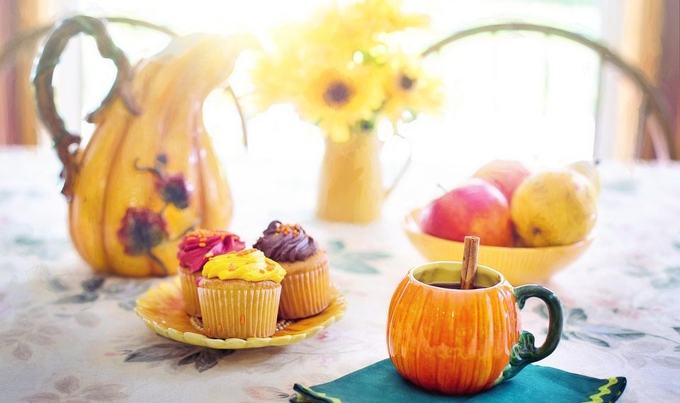 Cupcakes and apple cider on a floral table with autumn decorations.