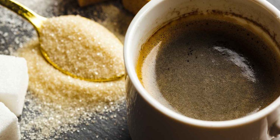Coffee cup with sugar cubes and a spoon of granulated sugar.