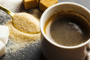 Coffee cup with sugar cubes and a spoon of granulated sugar.
