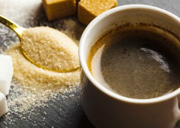 Coffee cup with sugar cubes and a spoon of granulated sugar.