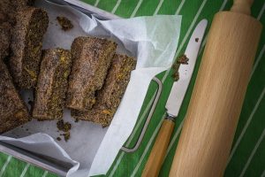 Homemade poppy seed bread arranged on parchment paper with a knife and rolling pin.