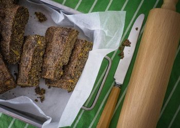 Homemade poppy seed bread arranged on parchment paper with a knife and rolling pin.