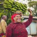 Woman joyfully carrying a bunch of bananas on her head.