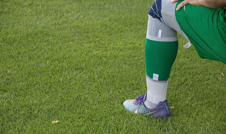 Athlete stretching on grass before a game.