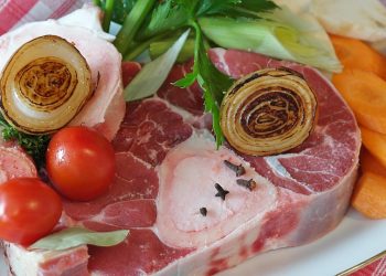 Steak with grilled onion, tomatoes, and carrots on a plate.