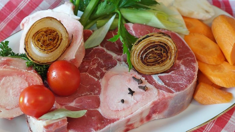 Steak with grilled onion, tomatoes, and carrots on a plate.