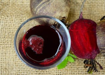 Beetroot juice and sliced beet on burlap background.