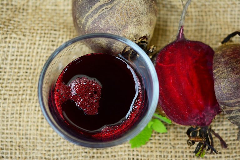 Beetroot juice and sliced beet on burlap background.