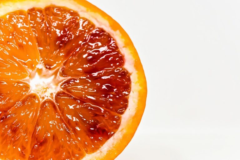 Half sliced blood orange on white background