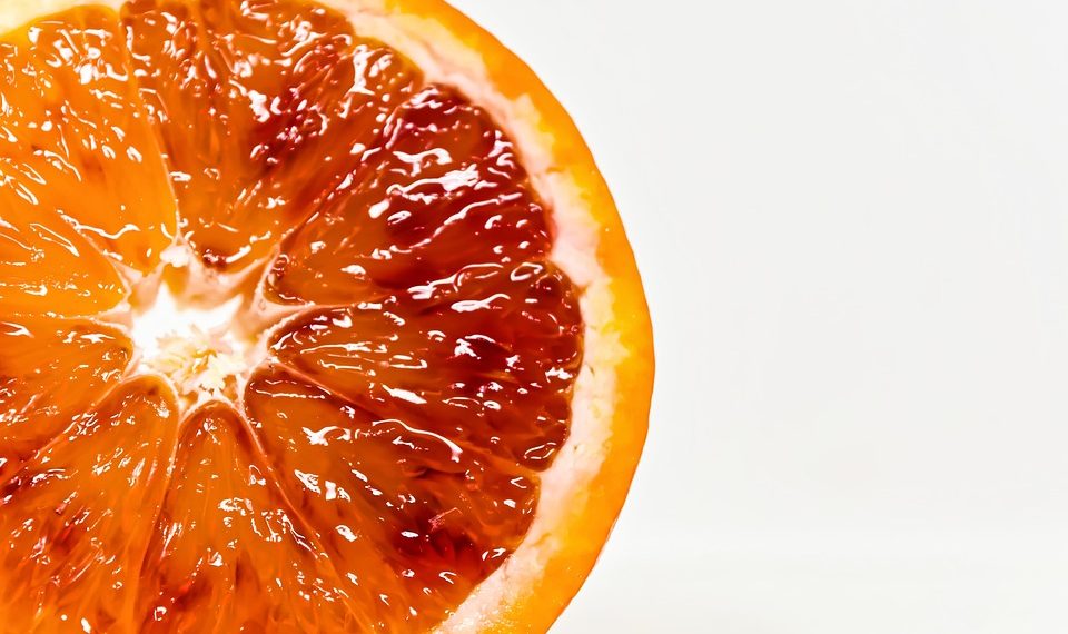 Half sliced blood orange on white background