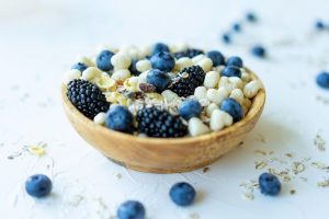 Bowl of mixed berries and nuts on a white surface.