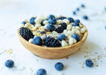 Bowl of mixed berries and nuts on a white surface.