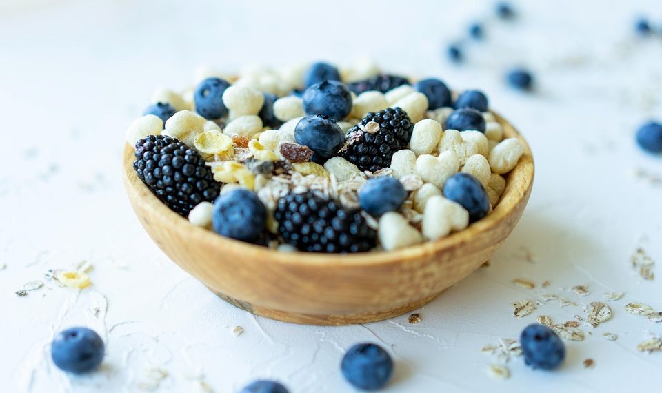 Bowl of mixed berries and nuts on a white surface.