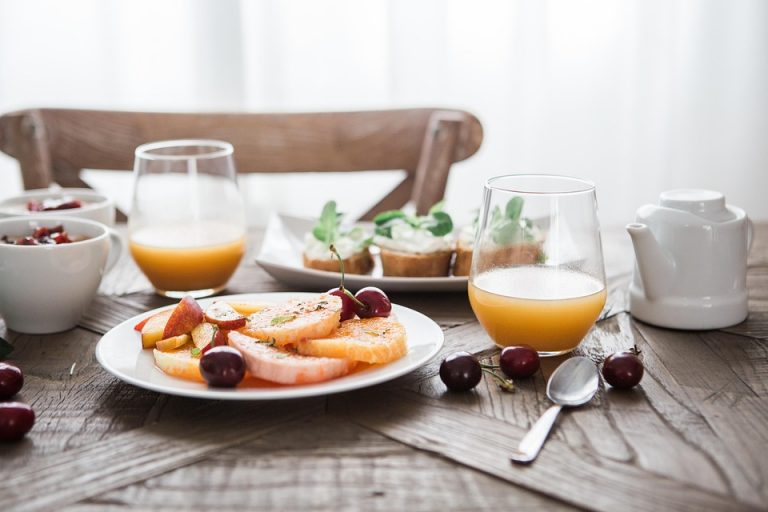 Plate with fresh fruit and juice on breakfast table.