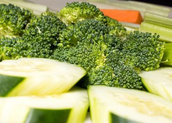 Fresh broccoli and sliced cucumbers presented with carrots and celery.