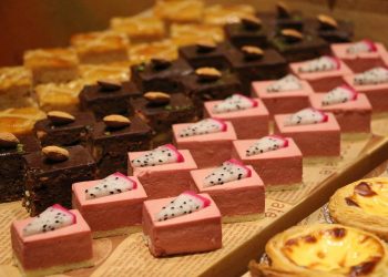 Assorted desserts with chocolate cake, pink mousse, and egg tarts displayed on a tray.