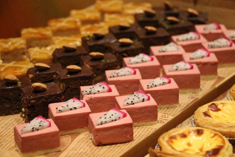 Assorted desserts with chocolate cake, pink mousse, and egg tarts displayed on a tray.