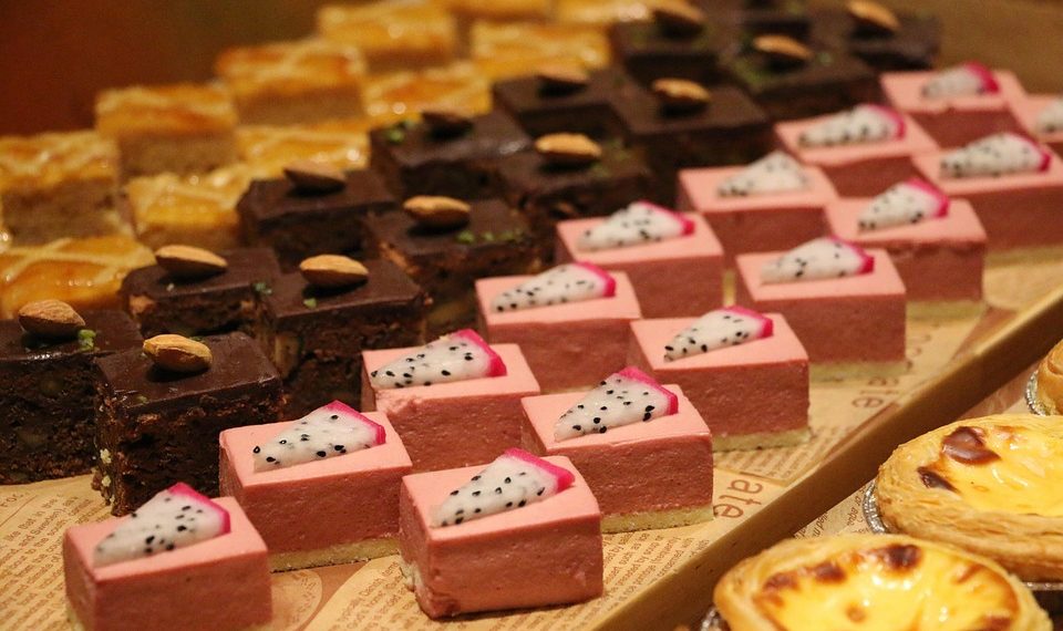 Assorted desserts with chocolate cake, pink mousse, and egg tarts displayed on a tray.