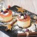 Festive mini cheesecakes with berries and powdered sugar on a slate platter.