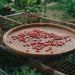 Drying red chilies on a woven bamboo tray outdoors.