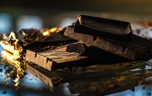 Dark chocolate bars unwrapped on a reflective surface.