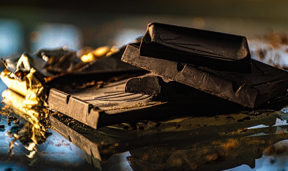 Dark chocolate bars unwrapped on a reflective surface.