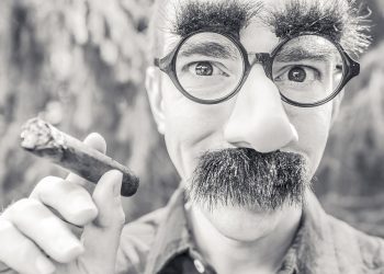 Man with humorous disguise holding a cigar.