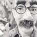 Man with humorous disguise holding a cigar.