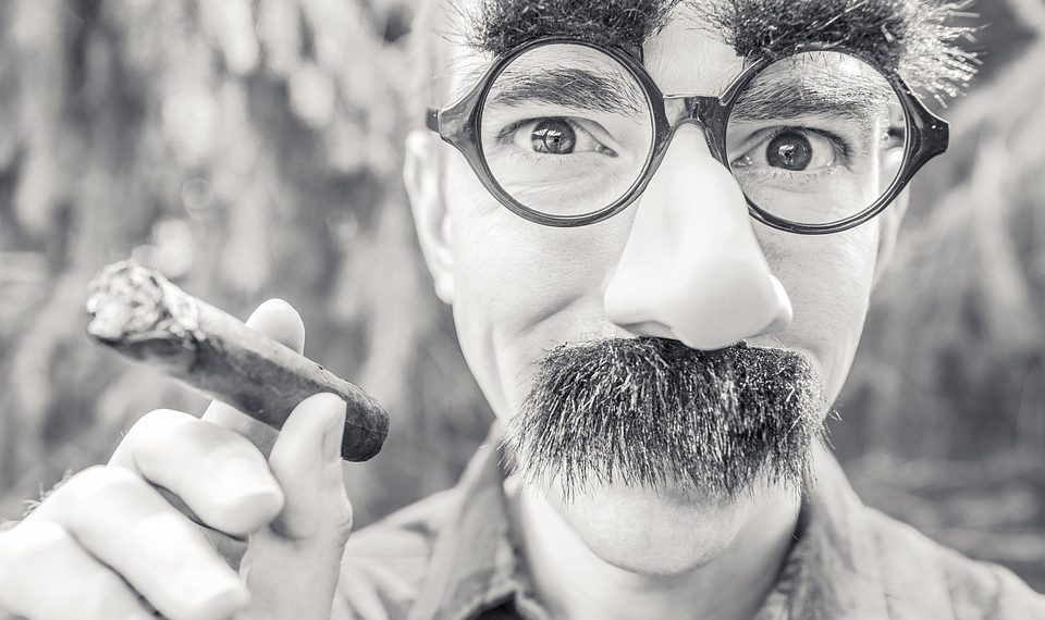 Man with humorous disguise holding a cigar.
