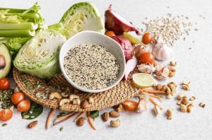 Fresh vegetables and nuts on a table with a bowl of quinoa.