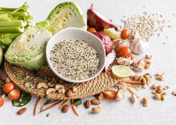 Fresh vegetables and nuts on a table with a bowl of quinoa.