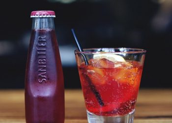 Chilled Sanbitter bottle and refreshing red drink with lemon slice.