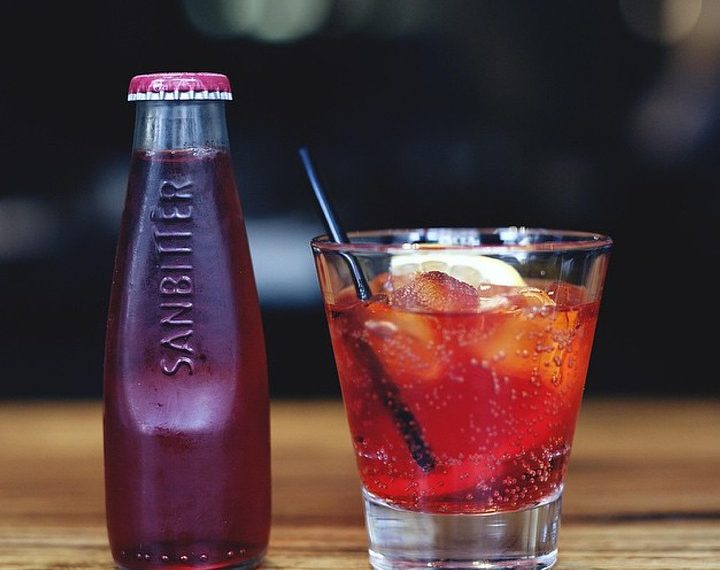 Chilled Sanbitter bottle and refreshing red drink with lemon slice.