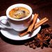 Steaming coffee with cinnamon sticks and star anise on a wooden table.
